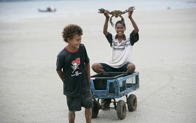 Two boys catching crabs on a beach.
