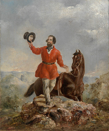 A bearded man wearing a bright red jacket and holding his top aloft stands on a rocky outcrop holding the reins of his horse.