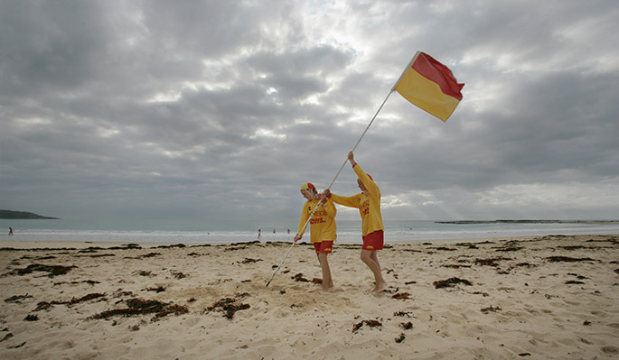 Two young people plant a lifesaving flag in almost deserted beach