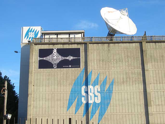 the outside of a large building which has a large white satellite dish and SBS logos on the side of the building.