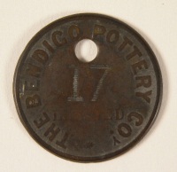Small circular copper token with a hole centre top. 'The Bendigo Pottery Co' is printed around the token's edge and the number '17' in the centre.