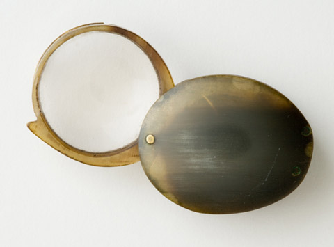 Circular magnifier hand-lens in a tortoiseshell frame, which is hinged to a circular tortoiseshell cover.