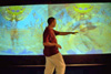 A visitor interacting with the projection of Aboriginal dancers and images