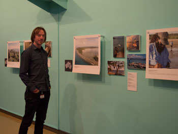 jono-lineen-3.jpg A man stands next to a gallery wall featuring a number of large photographs.