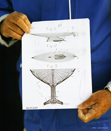 a close-up photo of two hands holding onto the design of a yacht keel