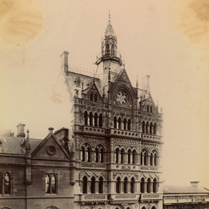 An ornate gothic building seven or eight storeys high with lower buildings on either side