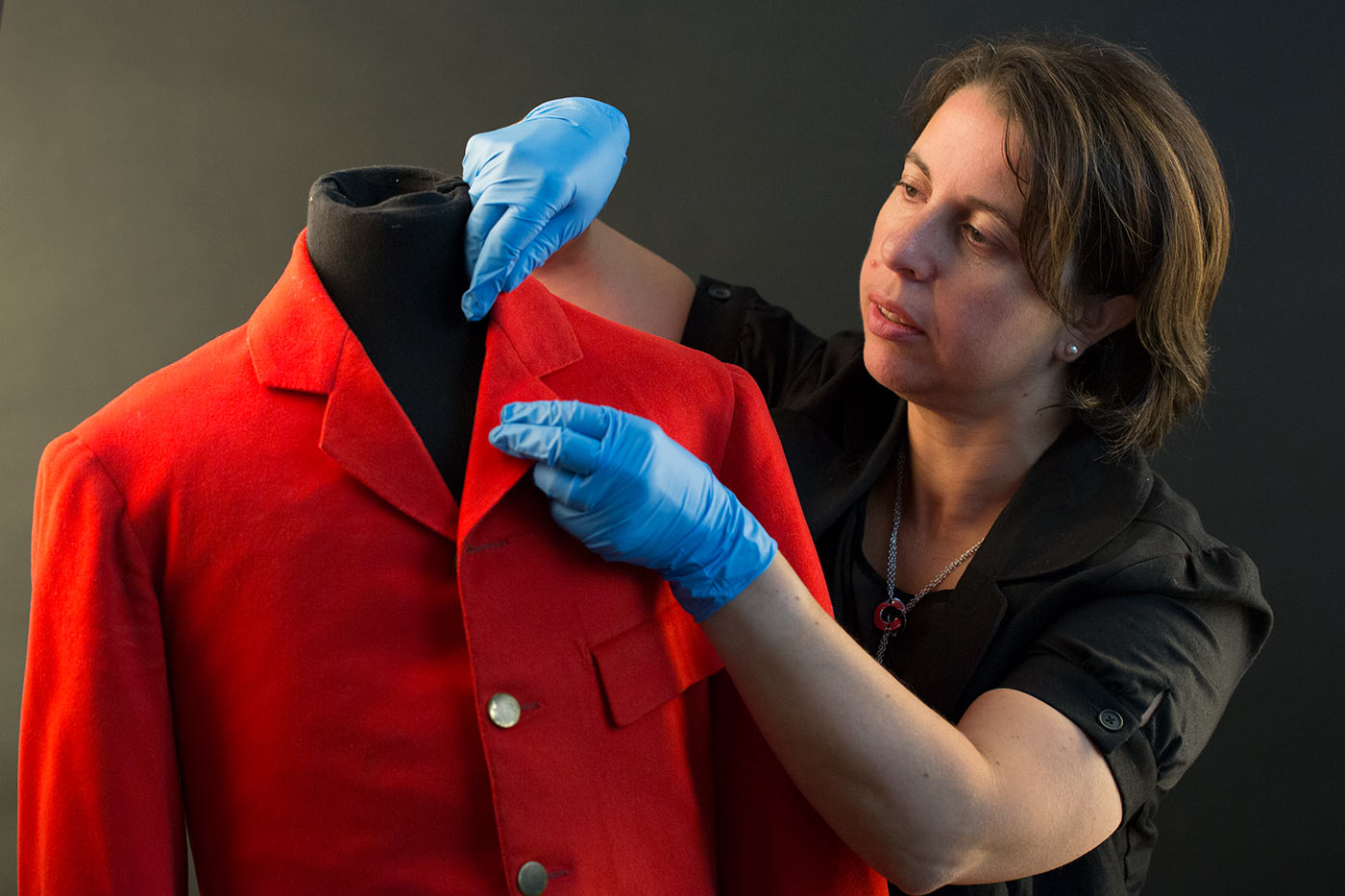 A woman is examining a red coat. - click to view larger image