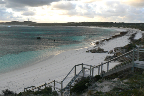 Crescent-shaped beach and bay, with wooden stairs in the foreground