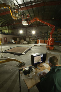 Two cranes and a camera linked to a computer screen are used to capture an image from above of a large Aboriginal dot painting.
