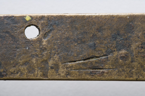 Close up image of a section of the back of the Leichhardt nameplate detailing the two score marks at the bottom close to the centre and the fastening hole at the top in the centre.