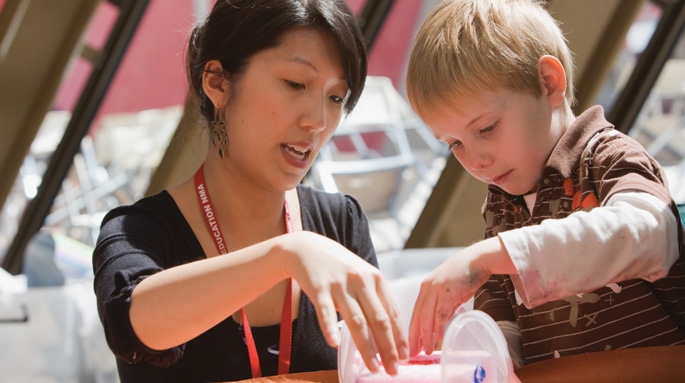 A volunteer assists a young Museum visitor at Discovery Space in the Hall.