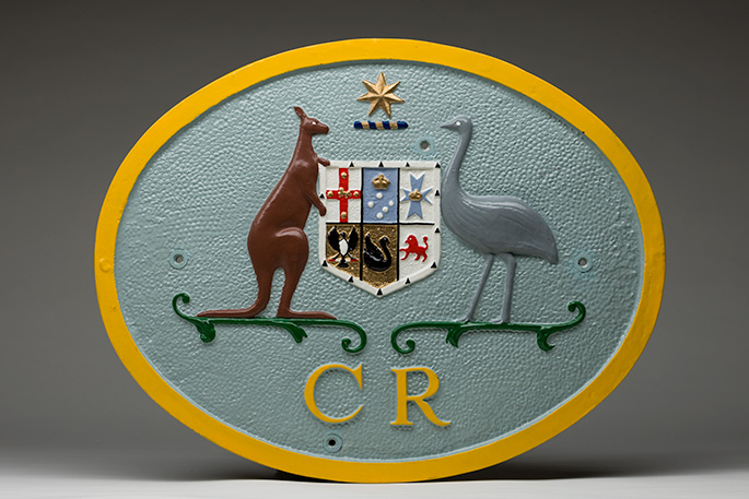 Oval plate with Australian coat of arms with the letters CR underneath.