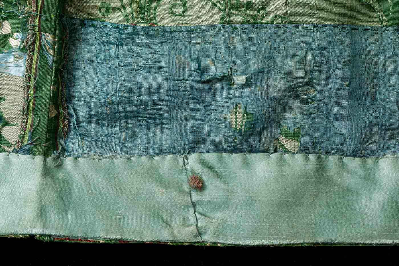 A detail image of the frayed hem of a green dress. - click to view larger image