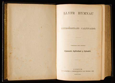 A Welsh hymnal, open. The left page is blank. The right page is headed 'LLYFR HYMNAU'