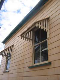 Side view of shaded, glass windows on a wooden house.