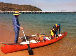 Canoe on the shore with four people.