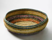 Basket Tjurtirangutjarra Purlka A large shallow basket made of bands of grasses which have been bound in plant material dyed in different colours and in strands of wool.
