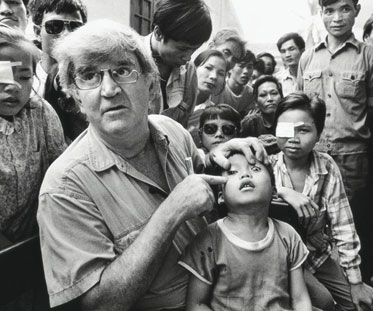 Fred Hollows points to the left eye of a young boy at a busy clinic in Vietnam.
