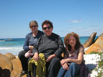 andy-greenslade-2.jpg Three women sitting on rocks with the ocean in the background.