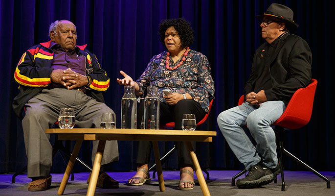 Two men and one woman sitting on a stage in discussion