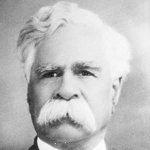 a black and white portrait photo of a white-haired man with a white moustache