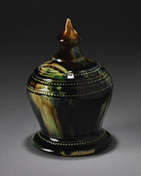 Dark green glazed, vase shaped ceramic money box with a circular base and spherical middle, tapeing to a cone-shaped knob.