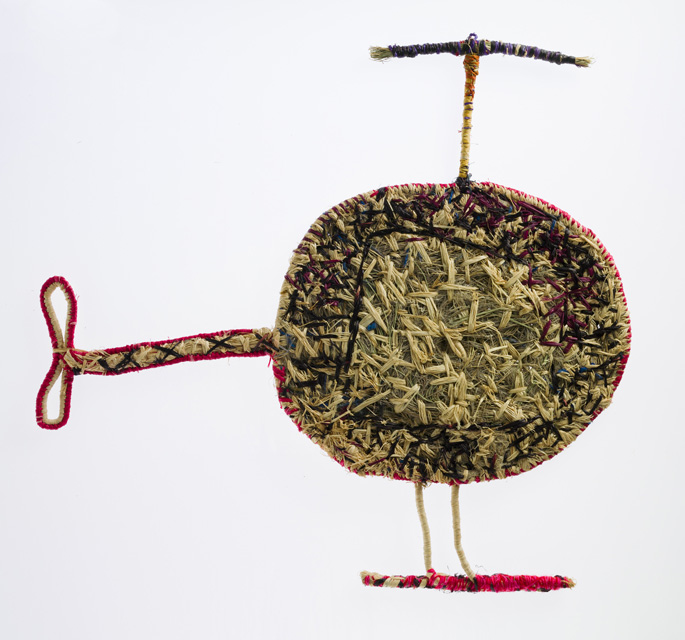 A sculpture depicting a helicopter. The sculpture is made of woven grass and plant material dyed in different colours.