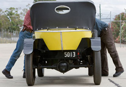 Rear view of Citroen car, showing conservators leaning into front, on either side.