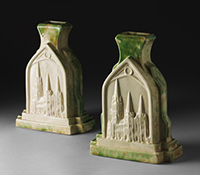 Two cream glazed ceramic vases shaped as Gothic arches on a rectangular base, with buttresses at two sides. The front shows the relief image of a church with three spires.