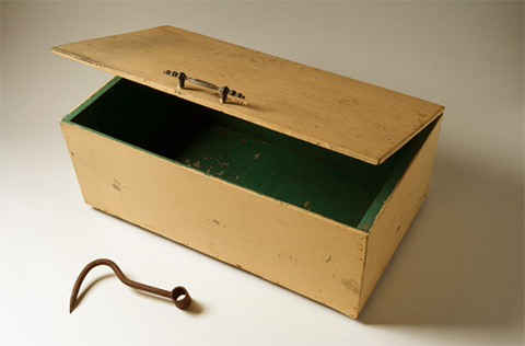 Image of a yellow box painted green inside and a rusted hook.