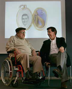 Kevin and John Hannan seated in front of large projected image of a locket with a photo of Les Darcy in it.