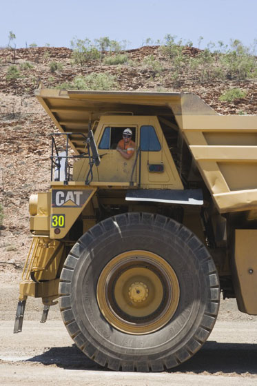 Side view of a man leaning out the window of an oversized truck.