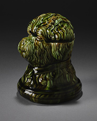 Green and fawn glazed jar designed in the shape of a dog's head.