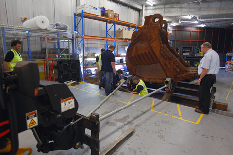 A smaller forklift attached to the bucket cradle with two long steel poles.