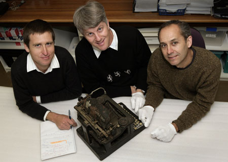 George Main, Noel Lane and Paul Peisley, in white gloves, inspect and make notes about a Smith & Bros typewriter, which belonged to Australian writer Dame Mary Gilmore