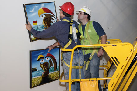 Conservation manager Eric Archer and Locations Registrar Patrick Baum recover paintings from the wall of the Administration corridor.