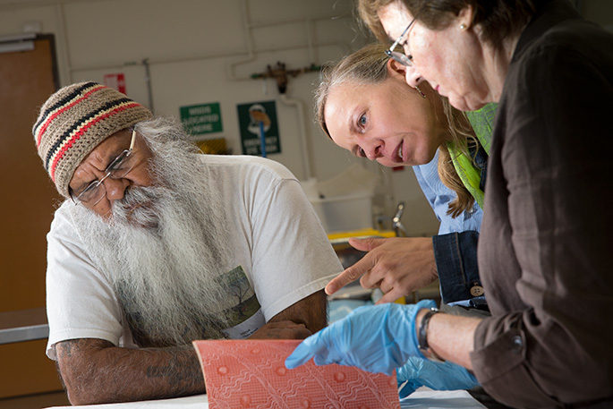 Man and two women inspecting a book
