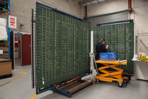 A photograph of a trading board with lists of stock prices and their codes, written in chalk.