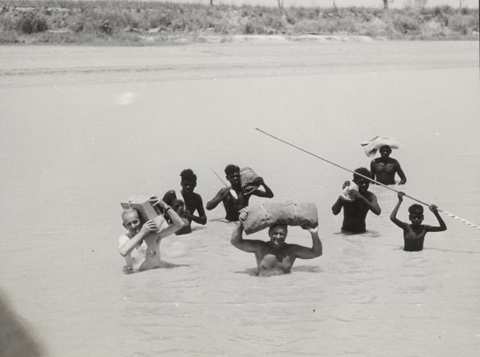 Charles P Mountford, Bill Harney and five Aboriginal men (unidentified) crossing the East Alligator River, 1948.