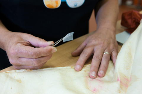 Deb Spoehr aligns the weave as the first step in stabilising a weakened area. A silk gauze backing will then be coated with a conservation quality adhesive and heat-set in position.