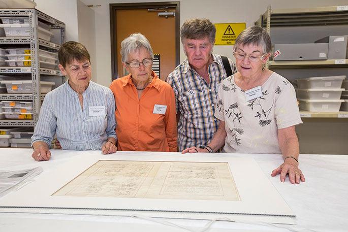 Four people standing behind a table with the letter of sympathy displayed in front of them