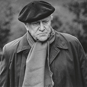 photo portrait taken outside of an elderly man in coat and scarf wearing a beret
