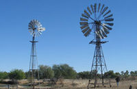 A windmill's grey sails set against a blue sky.
