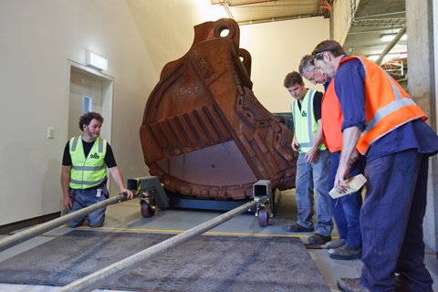 Museum staff inspecting sheets of plate steel placed over anything that might catch the cradle's wheels.