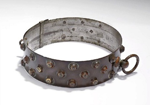 Copper patinated circular collar with raised studs on the outside and a small ring attached at the seam.