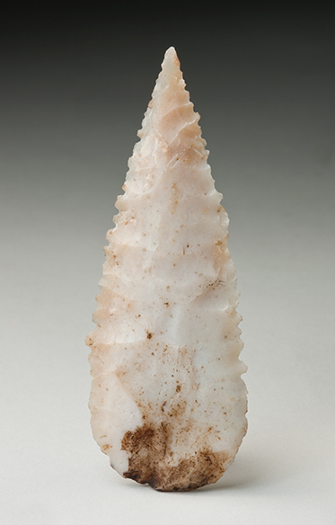 Spearhead flaked on both sides with serrated edges, rounded base and a sharp point at the opposite end.