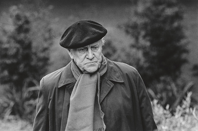 photo portrait taken outside of an elderly man in coat and scarf wearing a beret