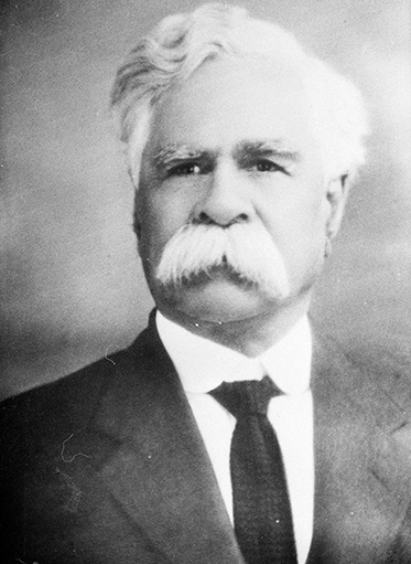 a black and white portrait photo of a white-haired man with a white moustache