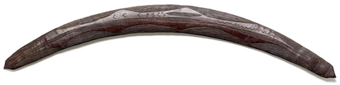 A wooden boomerang with pointed ends and engraved design.