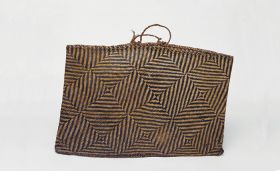 Basket made of light and dark brown flax strips plaited together in a geometric pattern, with handles made of twisted cord.